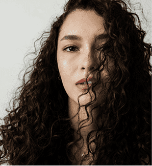 Curly-haired woman gazing confidently at the camera.